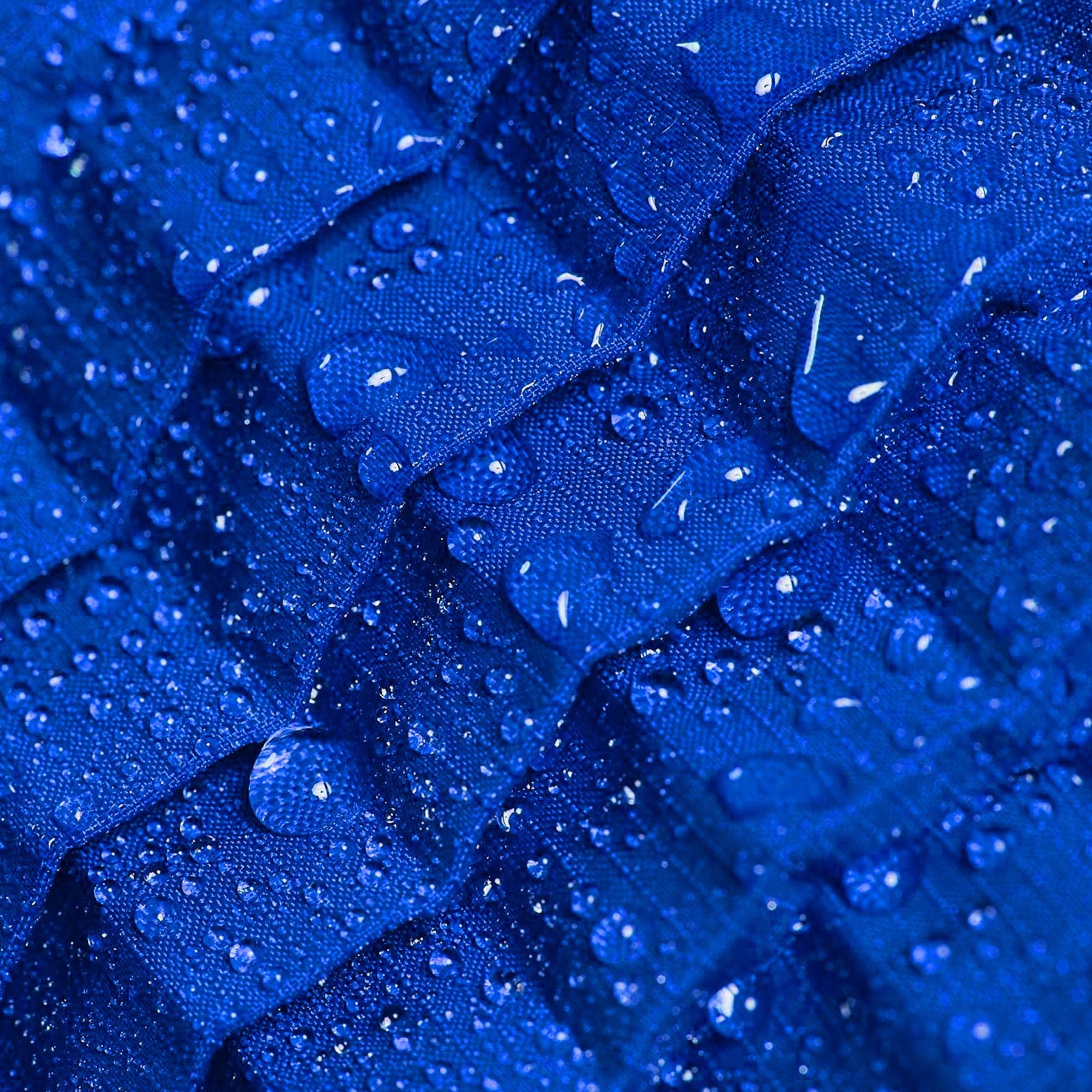 Macro view of Petit Pli's patented pleated fabric, water beading on its ripstop surface